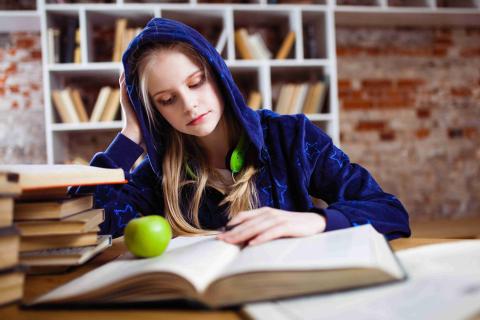 Middle-school student taking notes in front of an open book